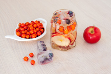 Water with sea buckthorn, forest berries and red apples