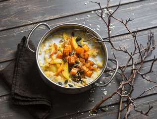 Gluten free pumpkin and apple porridge. Nut milk oatmeal with pumpkin, apples and honey on wooden brown background. Delicious healthy vegetarian breakfast