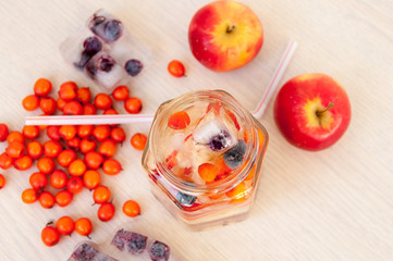 Water with sea buckthorn, forest berries and red apples