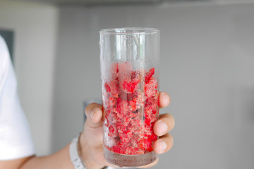 hand holding ice fresh raspberry in glass