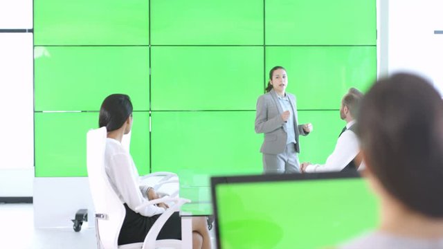  Business team in a meeting, interacting with large green screen video wall
