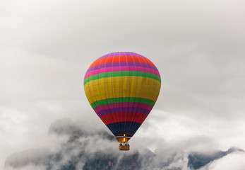 Fototapeta na wymiar Colorful hot air balloon fly over the mountains in the morning with thick fog.