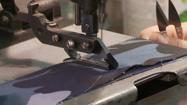 Close-up of a woman's hand making a military uniform on a sewing machine