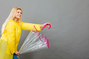 Happy woman wearing raincoat holding transparent umbrella