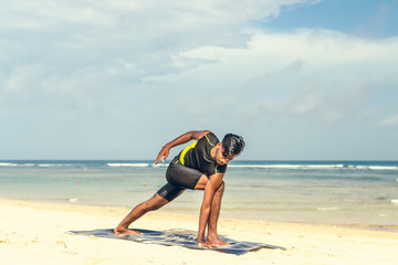 Asian yoga man practice yoga on the beach with a clear blue sky background. Yogi on the tropical beach of Bali island, Indonesia.