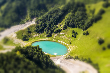 A beautiful round turquoise lake in a valley of high mountains.