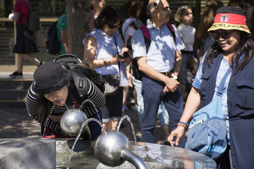 Fototapeta na wymiar Asian thai woman drinking water from public drinking water at garden square
