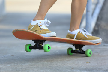 Skateboarder legs riding skateboard at skatepark