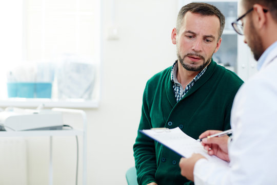 Anxious Patient Listening To His Doctor In Hospital After Examination