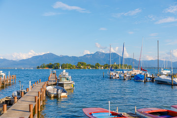 Boats at jetty at Seebruck with Fraueninsel at Lake Chiemsee, Bavaria on a sunny summer day