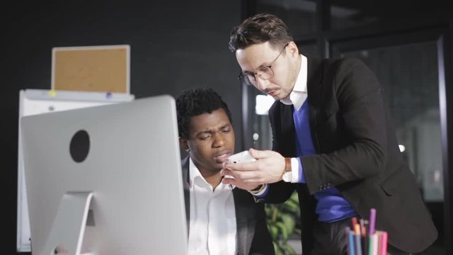 Boss shows his employee a pictures on the smartphone in the office