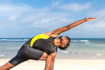 Asian yoga man practice yoga on the beach with a clear blue sky background. Yogi on the tropical beach of Bali island, Indonesia.