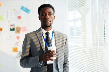 Confident young policeman in formalwear looking at camera on background of whiteboard with evidence