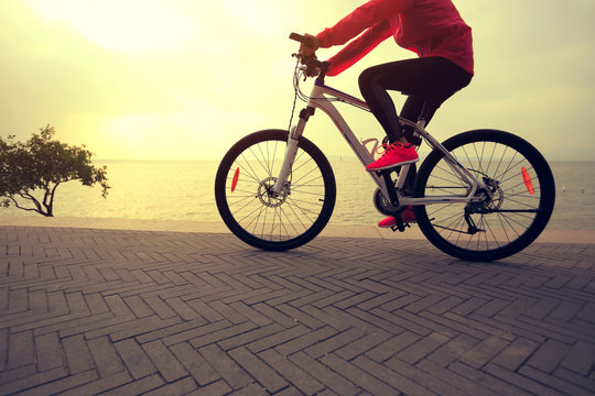 young woman cyclist cycling at sunrise seaside