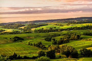 Midwestern view overlooking green fields at sunset. - obrazy, fototapety, plakaty