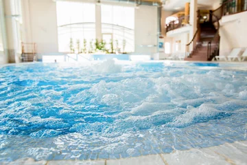 Fototapeten Waves and splashes in warm spa jacuzzi with nobody around © pressmaster