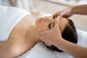 Tuinposter Calm girl having spa facial massage in luxurious beauty salon © pressmaster