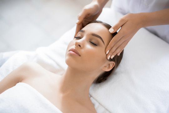 Young woman enjoying spa procedure with her face in luxurious massage salon
