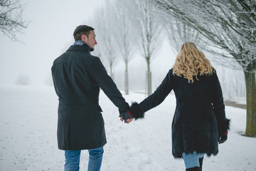 Glückliches Paar in Winterlandschaft gehen mit Wintermantel spazieren