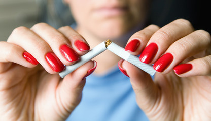 A girl with a beautiful manicure breaks a cigarette.