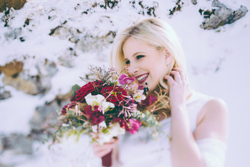 Blonde Frau mit Blumen auf dem Berg in Winterlandschaft