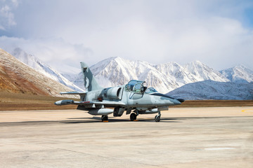 Military fighter jet parking on runway with snow mountain background