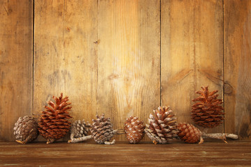 Holiday image with Christmas pine cones over wooden background