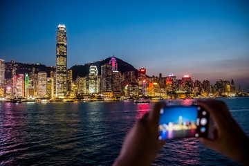 Fototapeta premium Woman using her Mobile Phone to take photo of city view, twilight Background