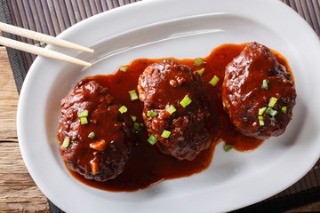 Japanese food: hamburg steak or hambagu with a spicy sauce on a plate macro. horizontal top view