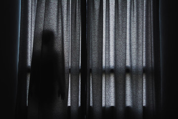 horror scene of woman's shadow standing hiding behind curtain