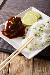 Japanese cuisine: hambagu steak with rice vermicelli and lime closeup on a plate. vertical