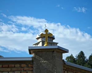 Obraz premium Cross on monastery fense and church dome in background