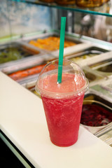 Fruit smoothie ready for sales in plastic cup with straw. Take away drinks concept. Fresh fruits juices at the public market. Various fresh fruit and vegetable salad bar healthy items. Healthy drink.
