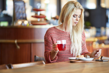 Portrait of young gorgeous female drinking tea and thoughtfully looking out of the coffee shop window