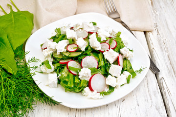 Salad with cheese and radishes in plate on light board