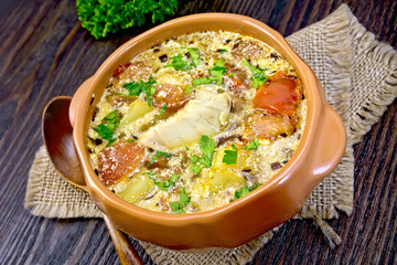 Soup fish with vegetables and herbs on dark board