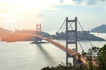 silhouette Tsing Ma double-decked suspension bridge between Ma Wan island and Tsing Yi island in Hong Kong, China at sunset and flare