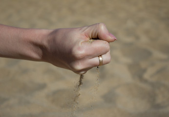 The woman pours the sand on the beach