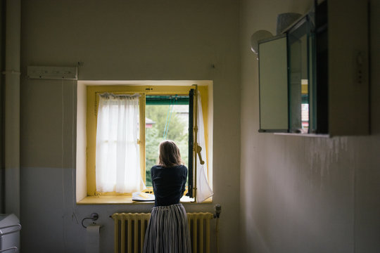Fille pos&eacute;e sur le rebord de la fen&ecirc;tre