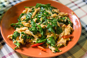 Liang vegetable fried with eggs delicious Thai local food, there are green leaves fried with eggs on orange plate
