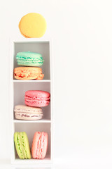 Colorful French macaroons on small wooden stand on white background