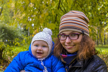 Mother with a joyful son in her arms in a public park