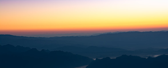 Naklejka na ściany i meble Panoramic view ofmountain layer in morning sun ray and winter fog.