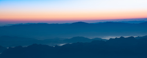 Fototapeta na wymiar Panoramic view ofmountain layer in morning sun ray and winter fog.