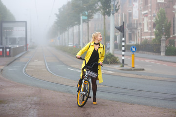 Young woman with bicycle in a misty city
