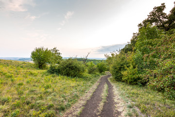 Sunset landscape panorama, hills in golden hour, small village in valley, beautiful colors and clouds.