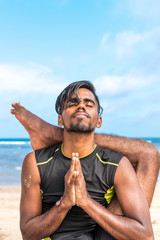 Asian yoga man practice yoga on the beach with a clear blue sky background. Yogi on the tropical beach of Bali island, Indonesia.