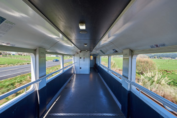 View of lush countryside from the inside of a viewing deck of a rail car