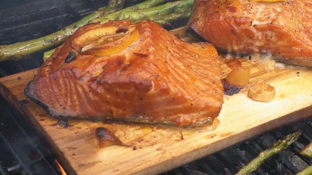 cedar plank salmon with lemon cooking on grill