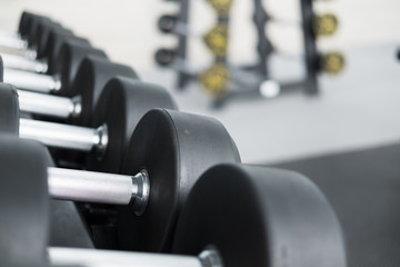Fototapeta premium Row of dumbbells in gym. Black dumbbell set in sport fitness center.